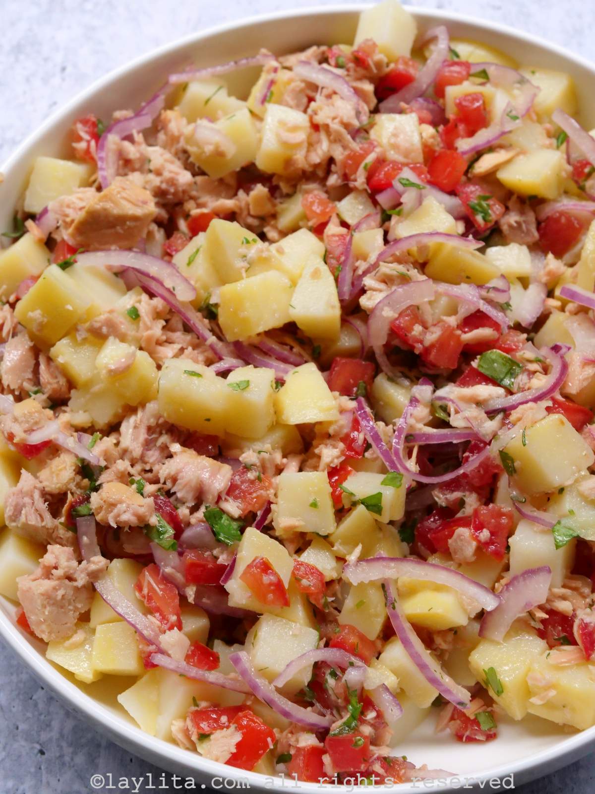 Close up of the tuna potato salad served in a white bowl.