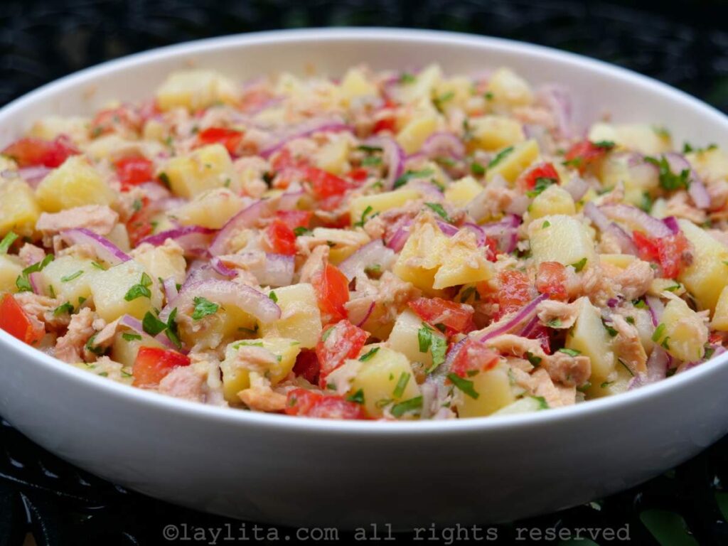 Side view of the tuna potato salad served in a shallow white dish with a black background