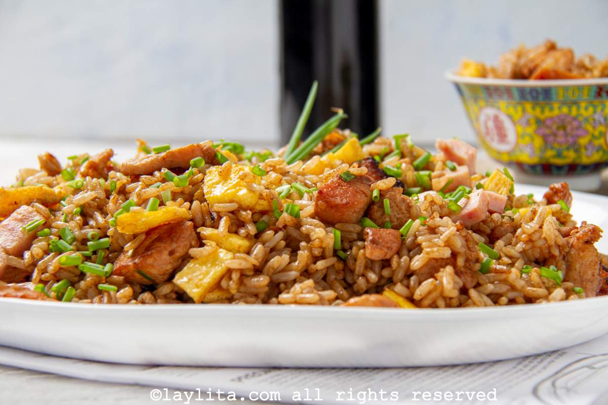 Side view of arroz chaufa on a large serving plate with a yellow bowl in the background. 