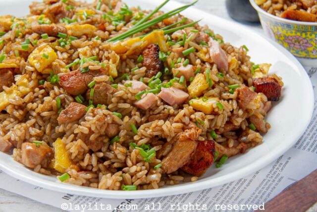 Peruvian chaufa fried rice on a white plate with green onions or chives on top
