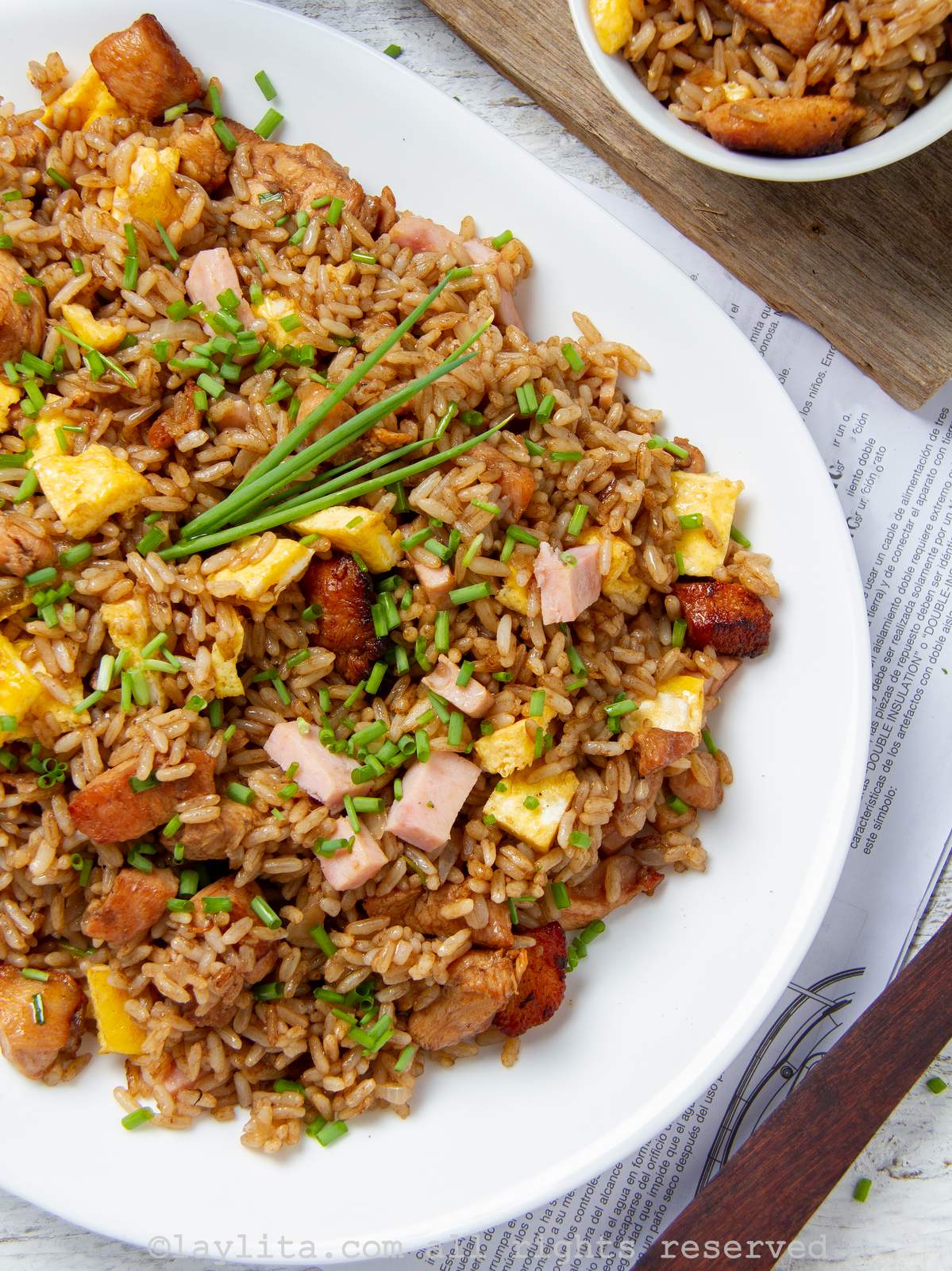 Overhead shot of Peruvian arroz chaufa fried rice on a serving platter with a small bowl of fried rice next to it.