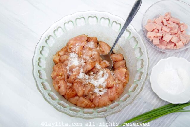 A bowl filled with chicken cubes marinating with soy sauce and spices
