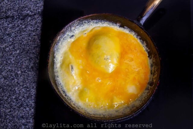 Cooking an omelet in a black frying pan