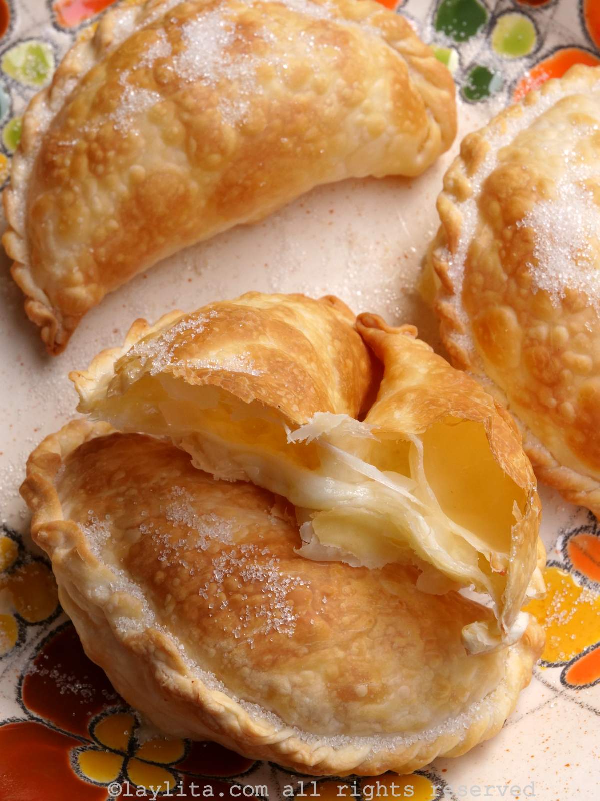 Overhead shot of air fryer cheese empanadas on an orange floral plate.