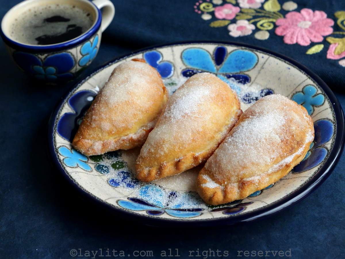 Air fryer empanadas de viento on a blue plate next to a small cup of coffee