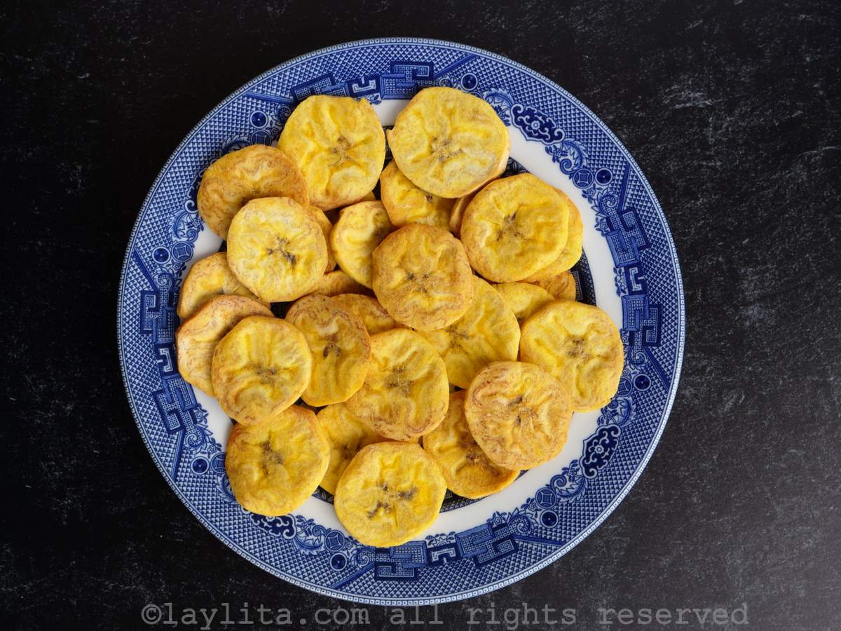 Air fryer chifles on a white and blue plate with a black background.
