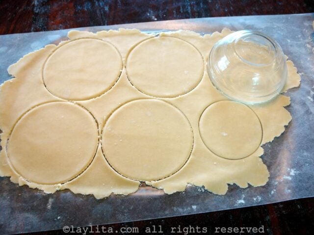 Empanada dough rolled out into a sheet with round cut out shapes using a bowl
