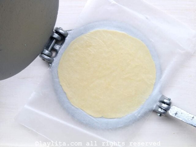 Tortilla press being use to flatten empanada dough