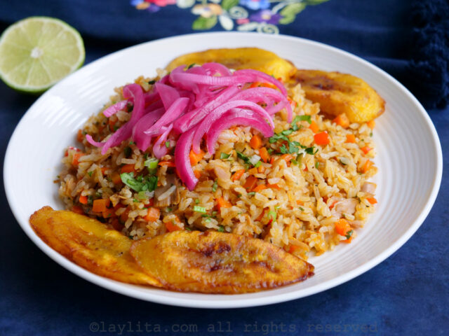 Side view of Ecuadorian tuan fish fried rice on a white plate served with a side of fried plantains and pickled red onions