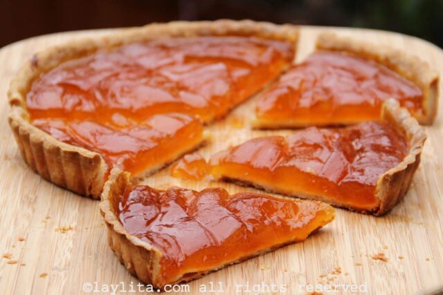 Babaco tart on a wooden background with three slices off the side.
