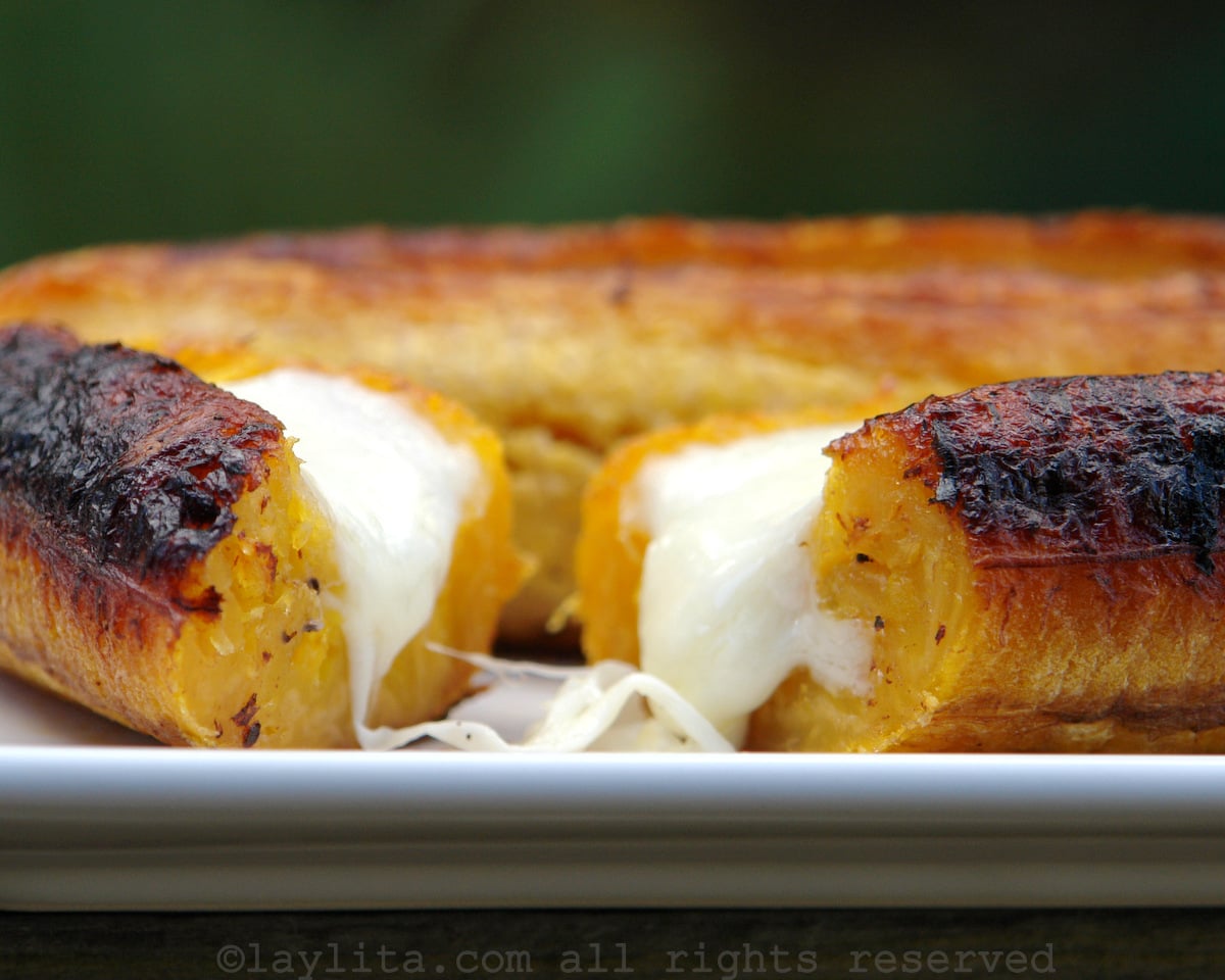 A baked ripe plantain stuffed with cheese, cut in half, on a while plate