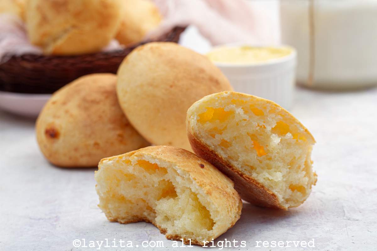 A Bolivian cuñape broken in half to show the inside with more bread in the background.