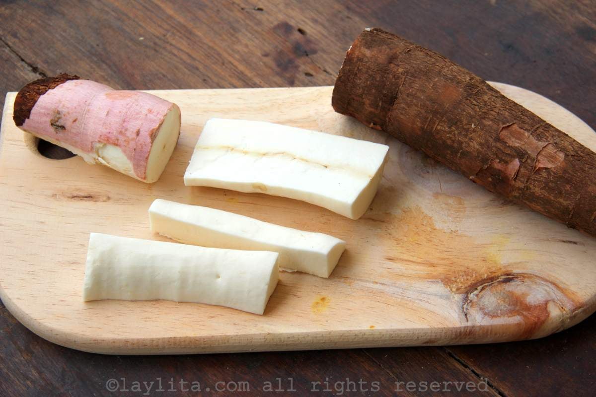 Fresh yuca with one sliced in half on a wooden board.