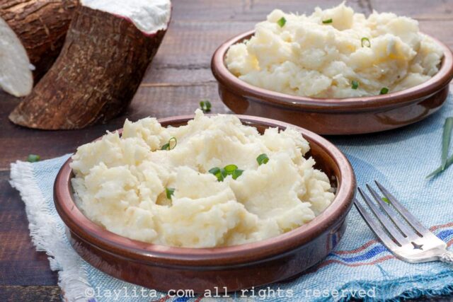 Two brown bowls with mashed yuca or cassava purée topped with green onions.