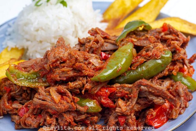 Close up view of ropa vieja shredded beef stew on a plate served with rice and plantains