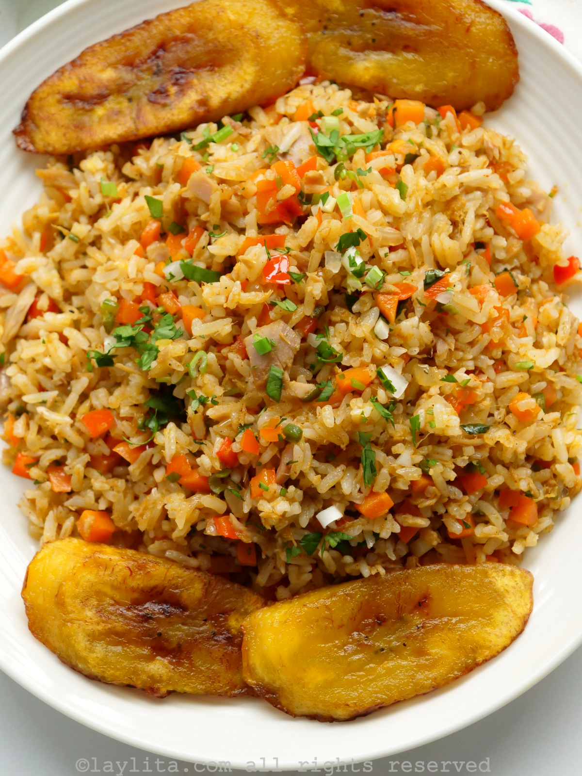 Close up of the tuna fried rice on a white plate with plantains on the side.