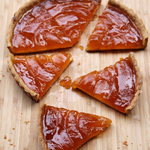 Overhead shot of babaco pie on a light wooden background with four slices off the side.