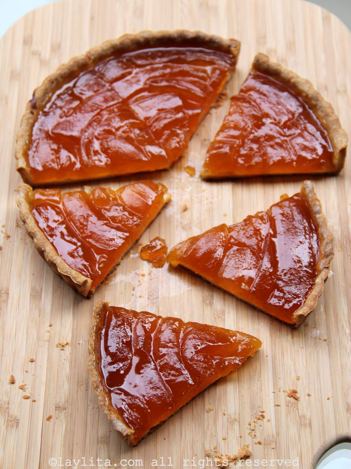 Overhead shot of babaco pie on a light wooden background with four slices off the side.