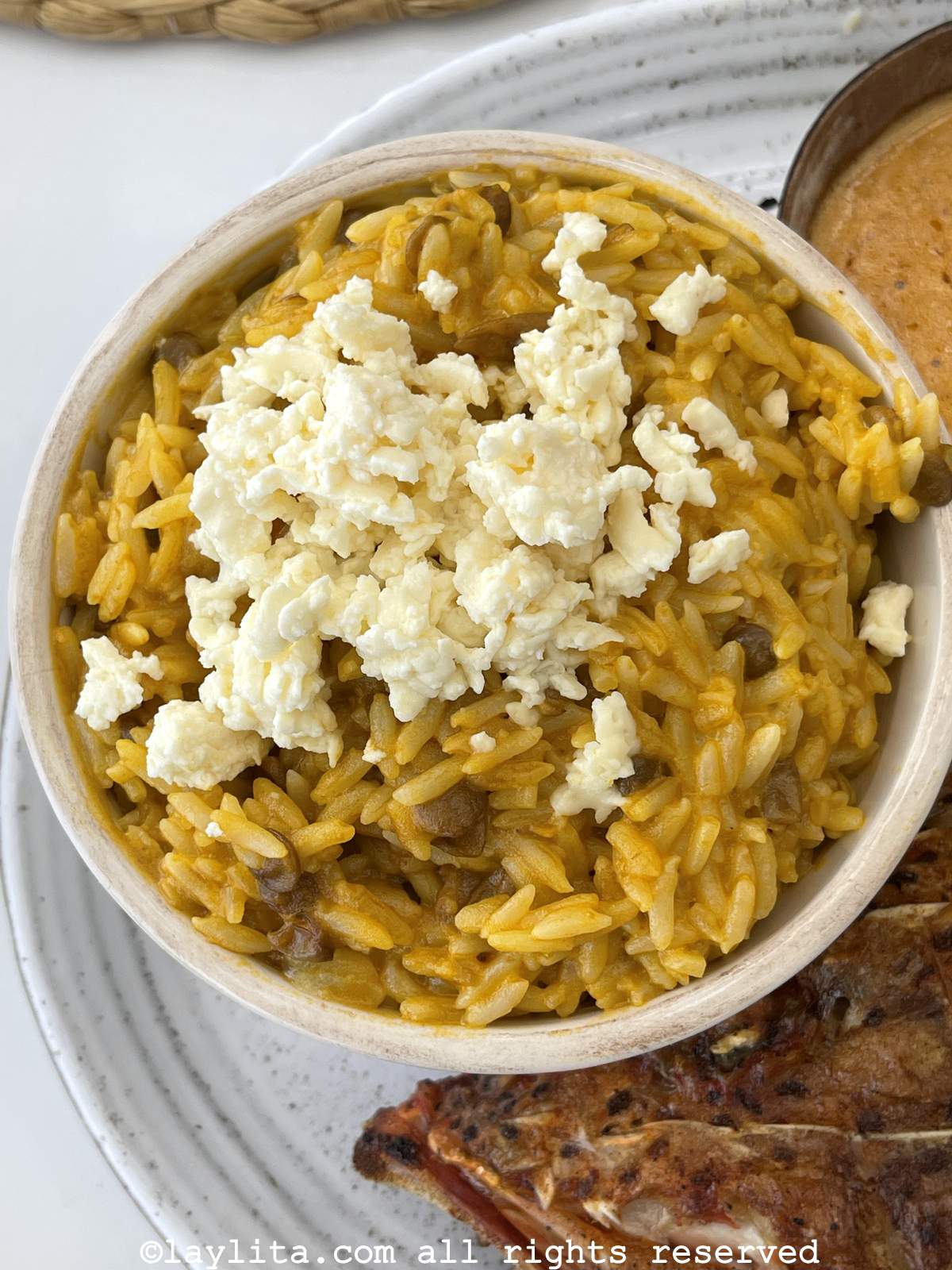 White bowl filled with Ecuadorian moro de lenteja or rice with lentils and topped with cheese