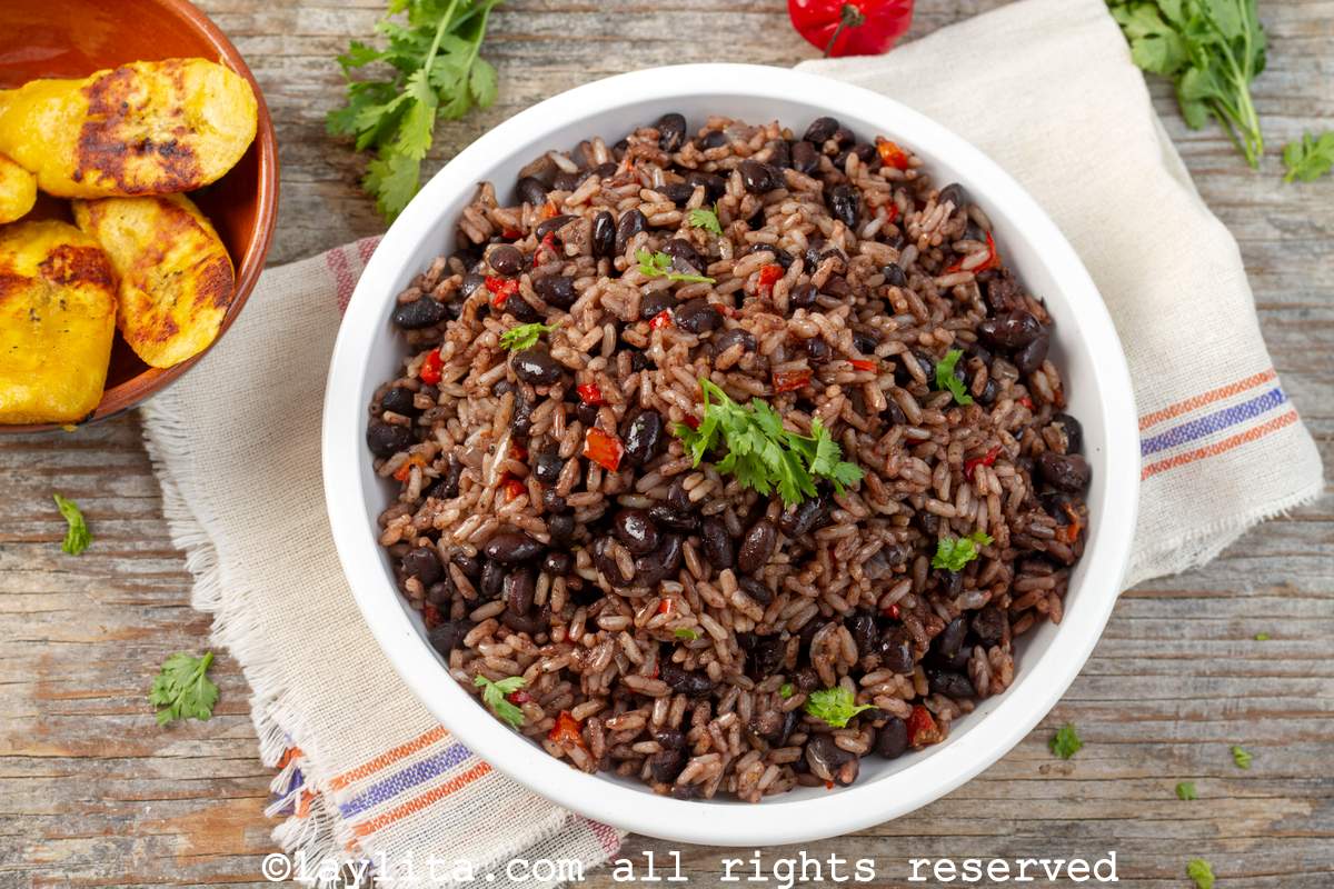 Overhead shot of Costa Rican rice and beans in a white bowl next to a small bowl of fried sweet plantains.