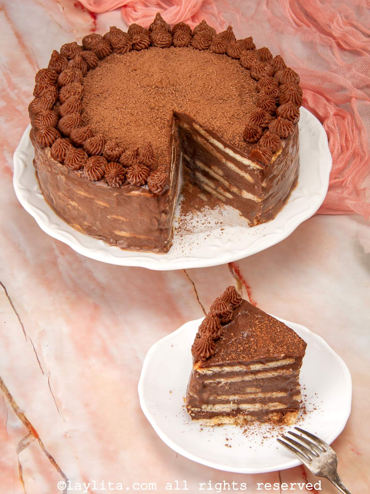 Overhead view of a slice of chocolate marquesa cake on a plate with the rest of the cake in the background