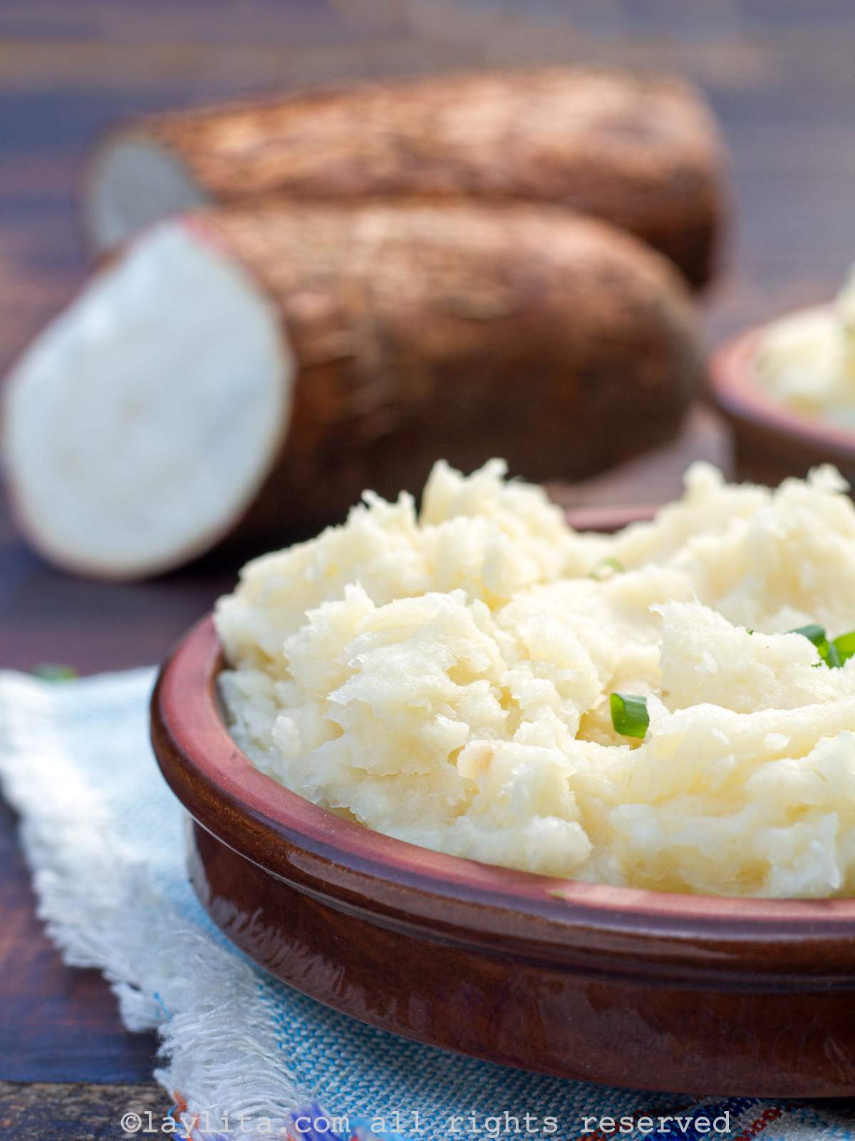 Close up side view of mashed yuca served in a brown shallow bowl.