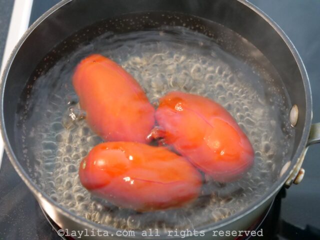 A pot filled with boiling water and three tomatoes