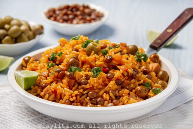 White shallow bowl filled with rice with pigeon peas with a lime wedge on the side.