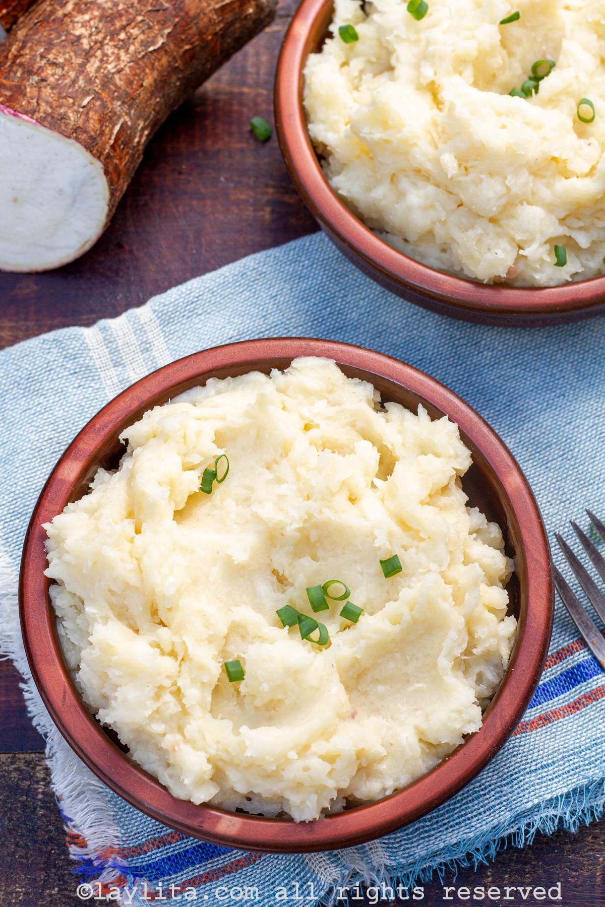 Overhead shot of a bowl of mashed yuca purée with green onions on top
