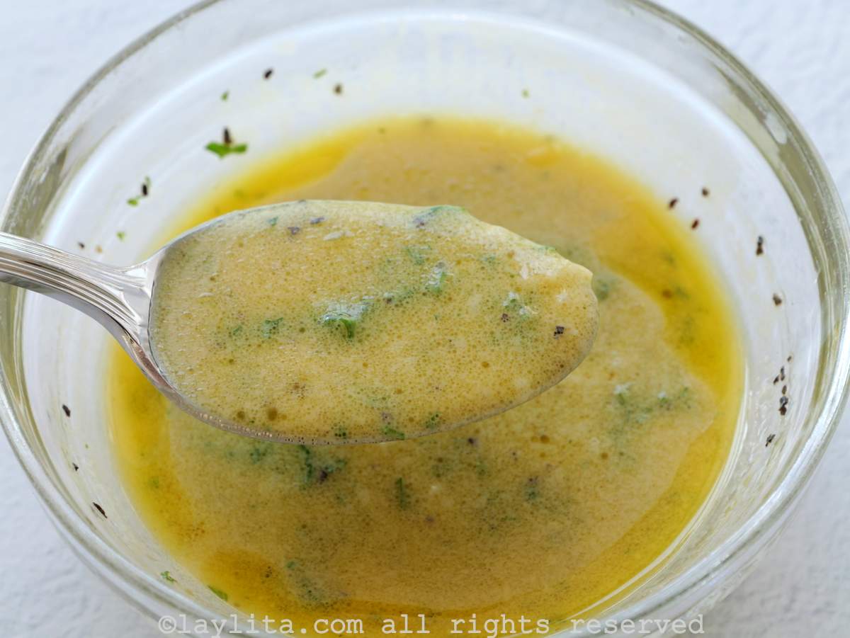 Red wine vinegar mustard vinaigrette for Cobb salad in a glass bowl with a spoonfu of the dressing out of the bowl