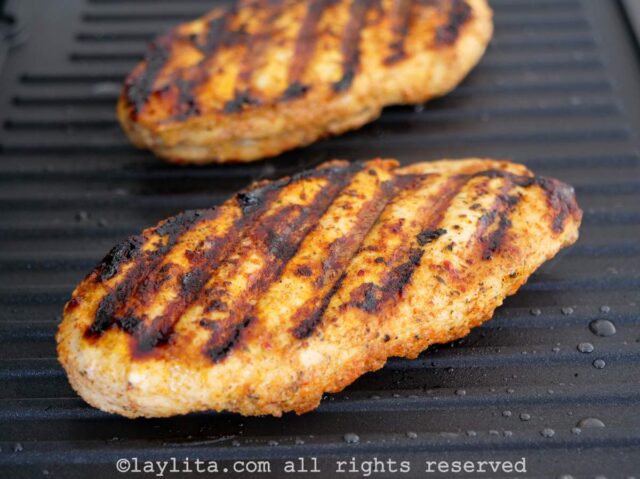 Two chicken breasts cooking on an indoor grill