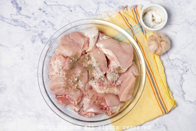 Skinless chicken thighs in a bowl seasoned with salt and pepper