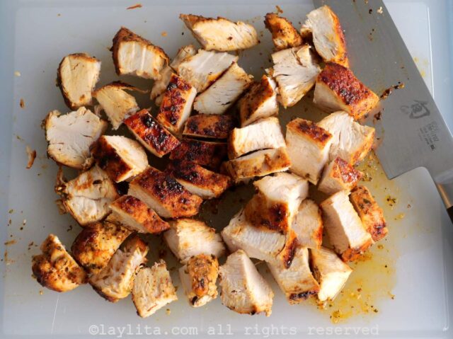 Grilled chicken cut into bite size pieces on a cutting board