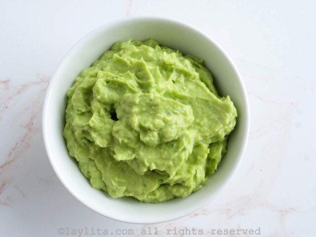Mashed or blended avocado as a topping for Chilean hot dogs in a white bowl