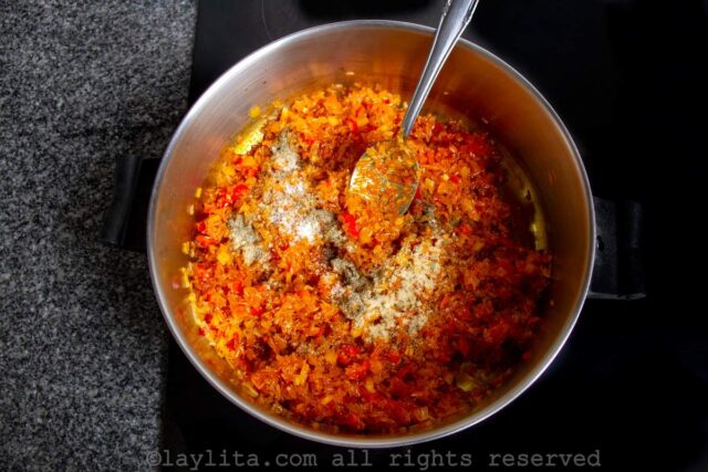 Rice being mixed in with the achiote sofrito