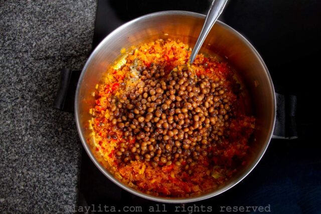 Adding the cooked pigeon peas to the pot