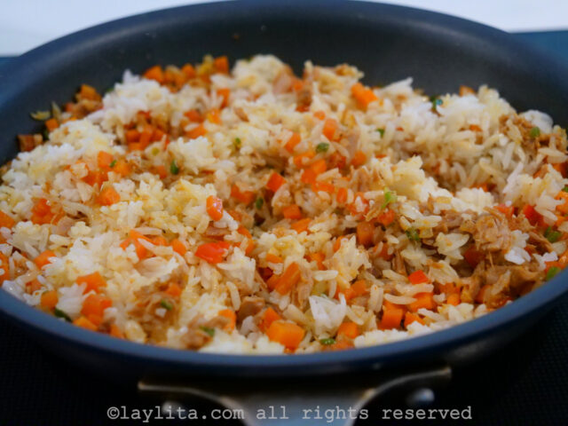 White rice being mixed into a skillet with vegetables and tuna fish