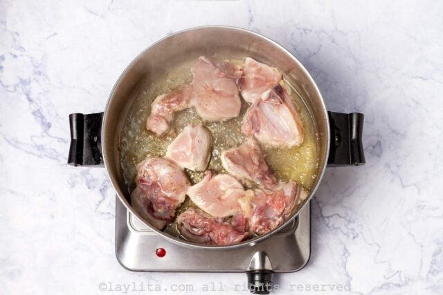 Cooking chicken thighs in garlic oil in a pan