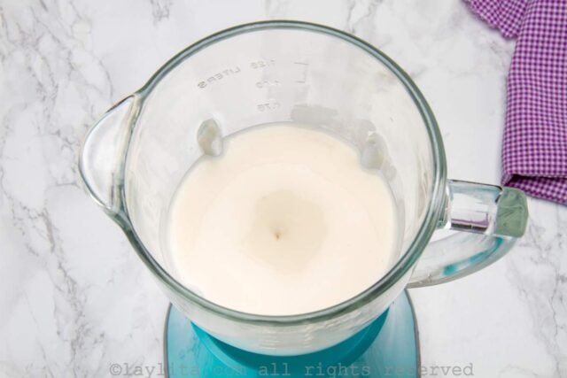 A white creamy mix blending in a blue blender