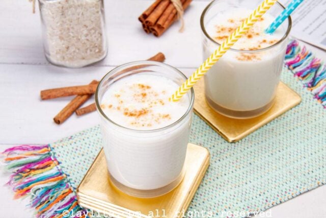 Two glasses of Venezuelan chicha on gold coasters both served with straws