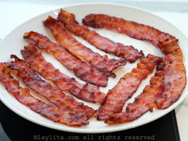 Cooked bacon slices on a white plate