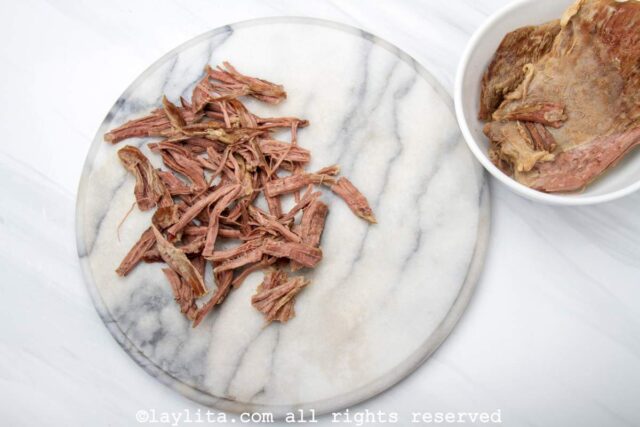 Shredding beef flank steak on white board