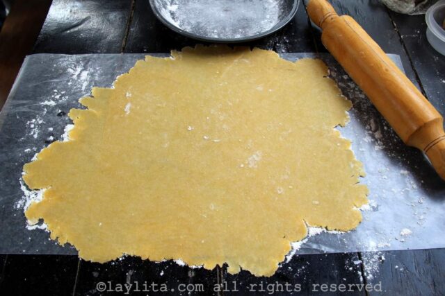 Rolling out sweet tart dough with a rolling pin on a wood table