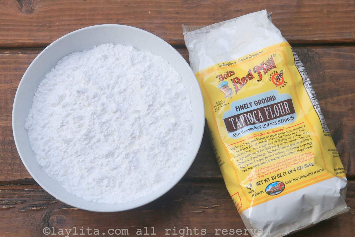 A bowl of tapioca starch next to a bag of tapioca starch on a wooden table