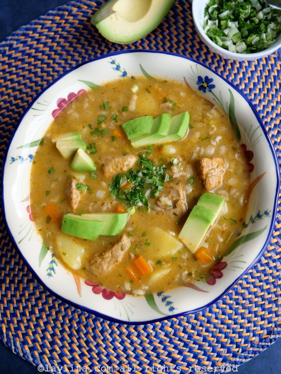 Flower designed bowl of oatmeal soup with pork on a blue and orange placemat served with avocado