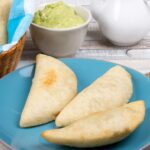 Overhead shot of three Venezuelan empanadas on a blue plate.
