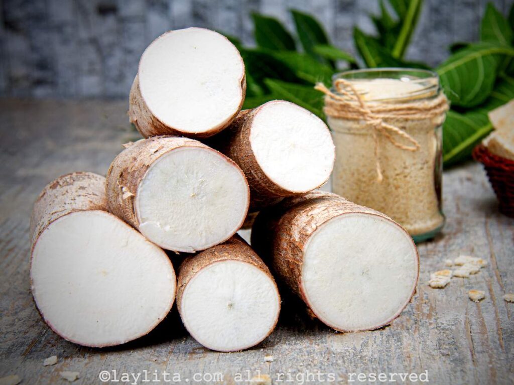 Fresh pieces of yuca cut in half all stacked on top of each other. 