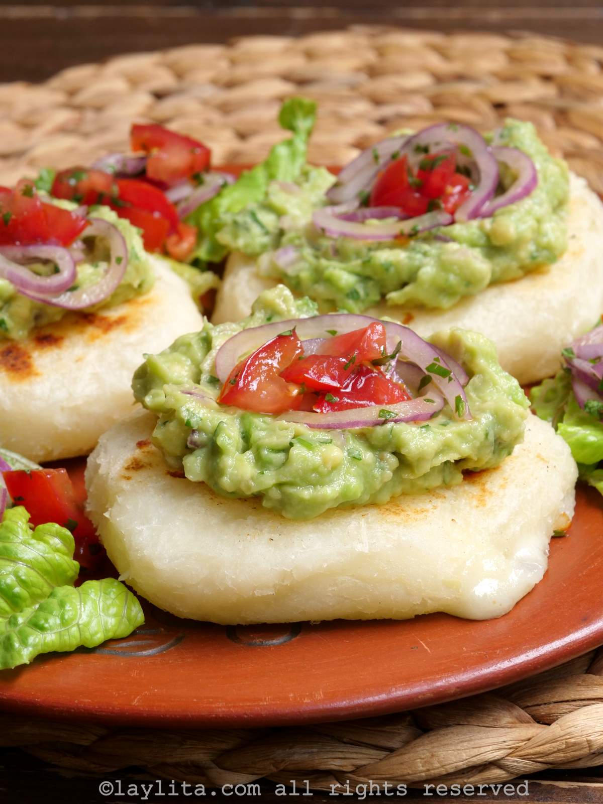 Close-up of tortilla de yuca or cheese stuffed cassava patties topped with avocado and tomato onion salsa