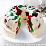Christmas jello served on a cake stand with one slice cut out.