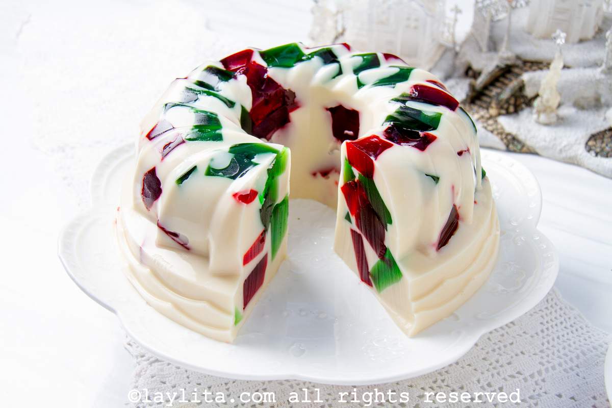 Christmas jello served on a cake stand with one slice cut out.